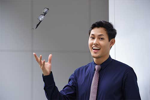 Young man tossing eyeglasses in air