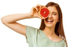 Woman holding grapefruit half up to face