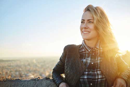 Woman leaning against stone wall outside