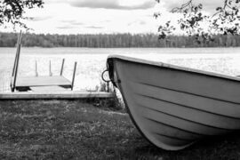 Black and white photo of rowboat pulled up on bank