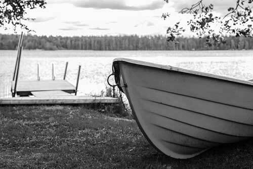 Black and white photo of rowboat pulled up on bank