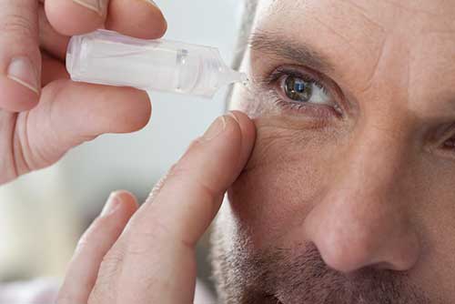 Man putting eye drops in eye