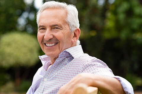 Older smiling man on park bench