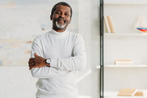 Older man with arms crossed in white shirt