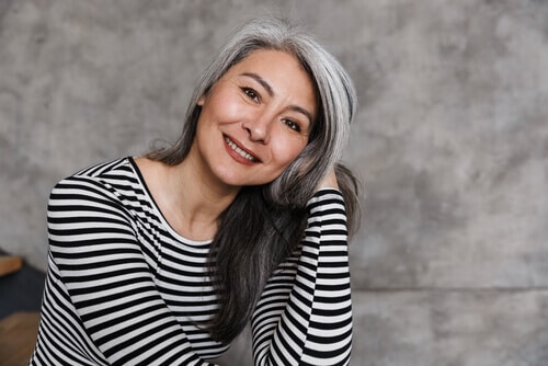 Middle aged woman with gray hair and gray wall background
