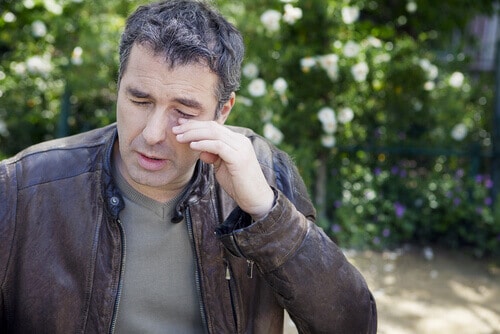man rubbing eyes due to allergies